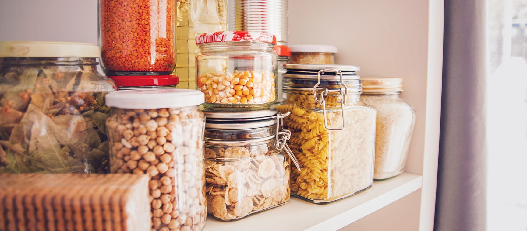 View inside a kitchen cupboard filled with jars and cans