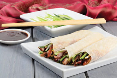 Chinese peking duck wrapped in pancakes with cucumber, spring onions and hoisin sauce