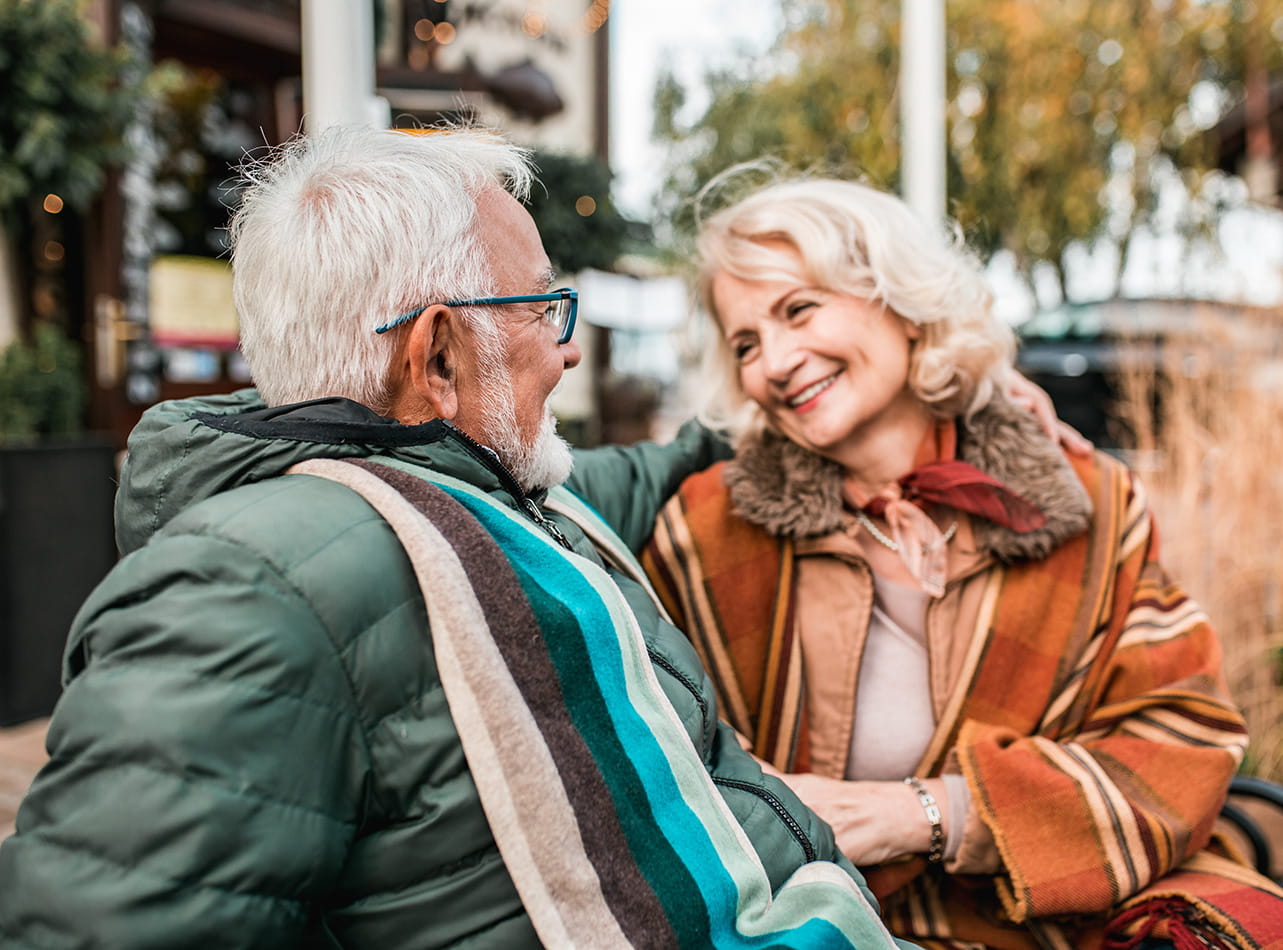 An older couple laughing together while wrapped in winter clothes